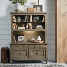 a bookcase with drawers and pictures on it in a room next to a door