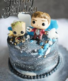 two figurines are sitting on top of a birthday cake