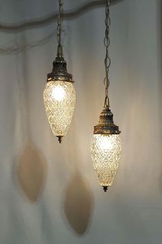 two lights hanging from chains on a wall