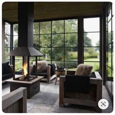 a living room filled with furniture and a fire place in front of large glass windows