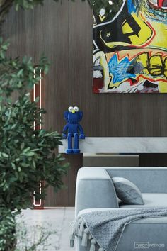 a blue teddy bear sitting on top of a couch in a living room next to a painting