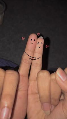 two fingers with faces drawn on them and hearts in the shape of smiley faces are shown