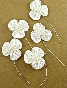 four white flowers are shown on a brown surface with thread in the middle and one is made out of paper