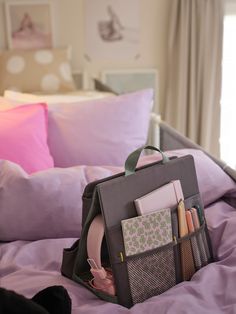 a bag is sitting on top of a bed with pink sheets and pillows in the background