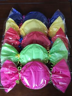 many different colored bags are wrapped in plastic and sitting on a wooden table with string