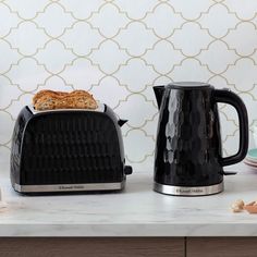 two toasters sitting on top of a counter next to plates and utensils