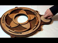 a person is working on a wooden object with gears in the shape of a flower