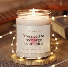 a candle that is sitting on a table with some string lights around it and the words you need to recharge your spirit