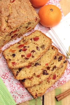 slices of fruit bread sitting next to oranges and cinnamon sticks on top of a table