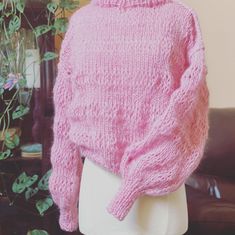 a mannequin wearing a pink knitted sweater and white skirt with flowers in the background