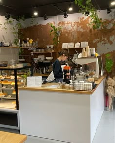 there is a woman behind the counter in this store that sells food and drink items