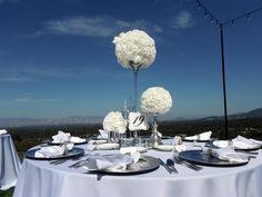 the table is set with white flowers and silverware