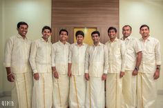 a group of men standing next to each other in front of a door wearing white clothing