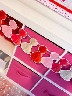 hearts are hanging from the ceiling above pink drawers