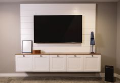 a flat screen tv mounted to the side of a white cabinet in a living room