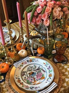 a table set with plates, candles and flowers