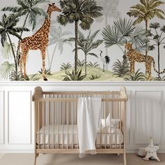 a baby's room with a giraffe mural on the wall next to a crib