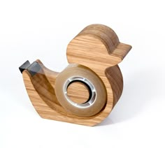 a small wooden bird with a metal ring on it's back end, sitting on a white surface