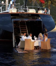 a group of people sitting at a table on top of a boat in the water