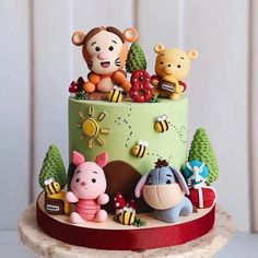 a cake with winnie the pooh figurines on top and decorations around it