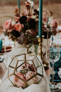 a table set with candles, flowers and glass vases for an elegant wedding reception