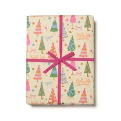 a present wrapped in white wrapping paper with pink ribbon and christmas trees on the front