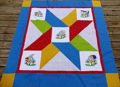 a quilted table runner with cars and trucks on it, sitting on a wooden deck