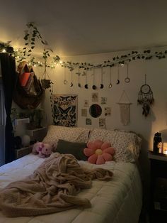 an unmade bed in a bedroom with lights on the wall and decorations above it