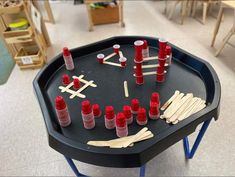 a black table topped with lots of red cups and sticks