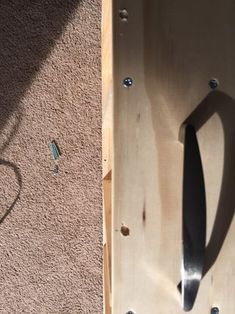 the shadow of a knife is cast on a piece of wood that has been nailed to it