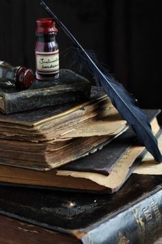 an old book with a feather quill and ink bottle on top