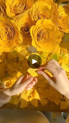 two hands touching each other with yellow flowers in the background and text overlay that reads, how to make paper roses