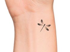 a small black dragonfly tattoo on the wrist