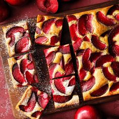 sliced up fruit pizza on a cutting board next to some apples and powdered sugar