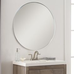 a bathroom vanity with a round mirror above it