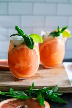 two grapefruit margaritas with mint garnish on a cutting board