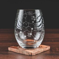 the stemless glass is sitting on top of a wooden coaster with an image of chemical diagrams