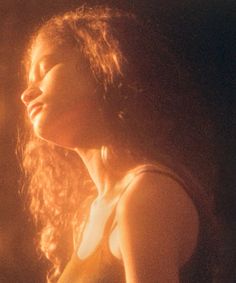 a woman with long hair standing in front of a fire