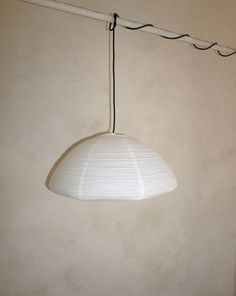 a white lamp hanging from a ceiling in a room with beige walls and flooring