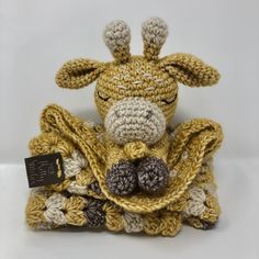 a crocheted giraffe sitting on top of a pile of yarns