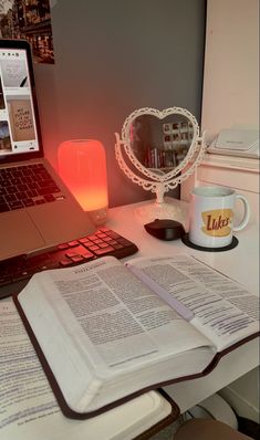 an open book sitting on top of a desk next to a laptop computer and lamp