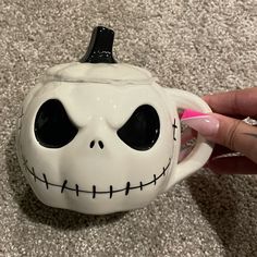 someone is holding a coffee mug with a skull on it