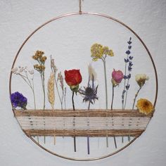 a wooden bench with flowers on it in front of a white wall and a circular frame