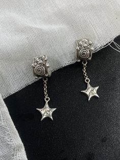 Handcrafted from sterling silver, these enchanting earrings are a testament to celestial beauty. The mystical spiral swirl detailing on the stud-style hoops symbolises the infinite wonders of the universe. stars dangle from the hoops, connected by a dancing chain. With every movement, the stars sway gracefully, evoking the twinkling wonder of a starlit sky. Despite their ethereal appearance, these earrings are comfortable weight yet substantial, making them perfect for adorning the human vessel with a touch of celestial magic. EACH PIECE HANDCRAFTED MINDFULLY WITH LOVE SOLID STERLING SILVER Celestial Style Silver Tarnish-resistant Jewelry, Celestial Star-shaped Sterling Silver Jewelry, Celestial Sterling Silver Drop Earrings, Whimsical Star-shaped Jewelry With Star Charm, Cinnamon Stars, Adjustable Star-shaped Sterling Silver Earrings, Starlit Sky, Celestial Magic, Stud Style