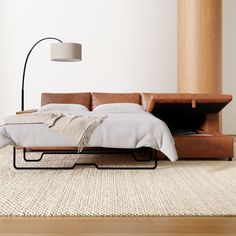 a bed sitting on top of a wooden floor next to a lamp and a rug