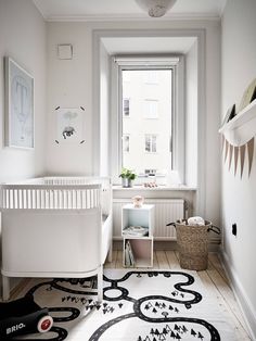 a baby's room with a white crib, black and white rug, and large window