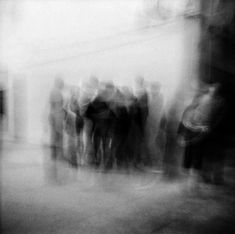 black and white photograph of people standing in front of a building with blurry background