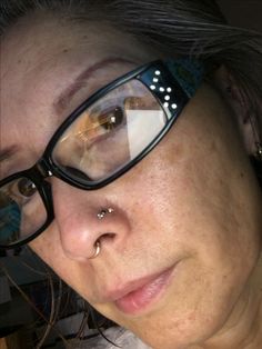 a woman with glasses and piercings on her nose