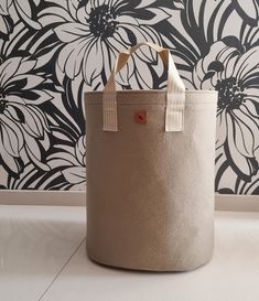 a large canvas bag sitting on the floor in front of a wall with flowers painted on it