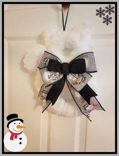 a snowman wreath hanging on the front door with a black bow and white ribbon